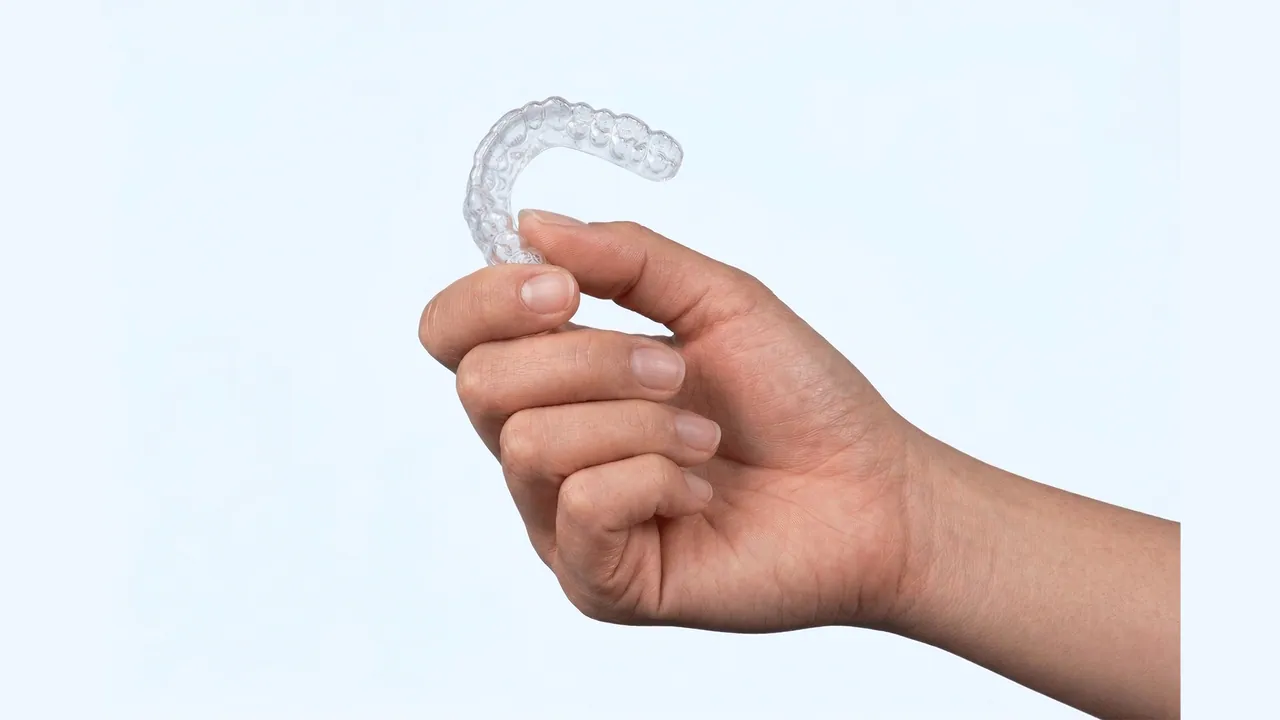 A hand holding a clear aligner